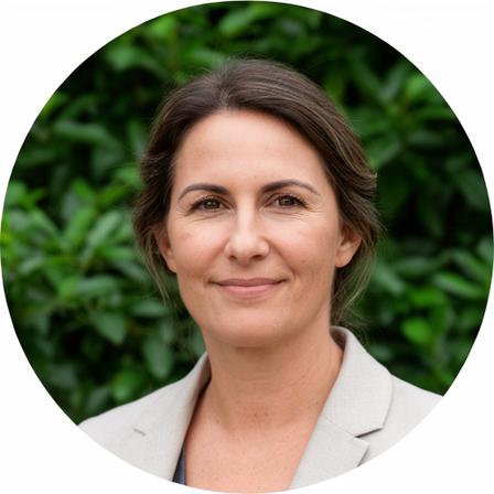Geschäftsführerin Verena Holzer im Gartenbetrieb mit Arbeitskleidung und ruhigem Blick vor grüner Pflanzenkulisse